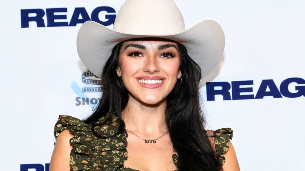 Alexis Wilkins smiling in a cream cowboy hat at a public event