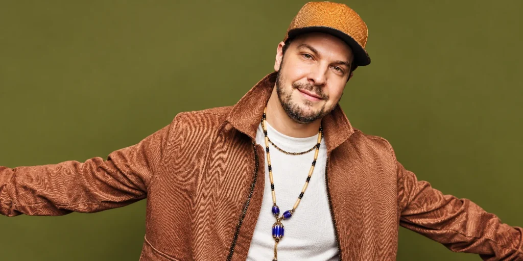 Gavin DeGraw wearing a brown jacket and cap