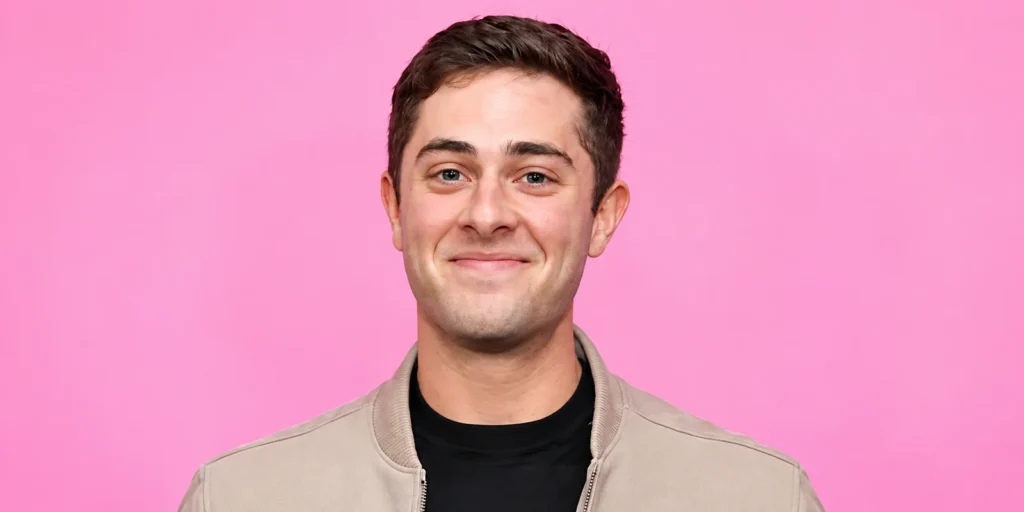 Jaren Lewison smiling in a beige jacket against a pink background