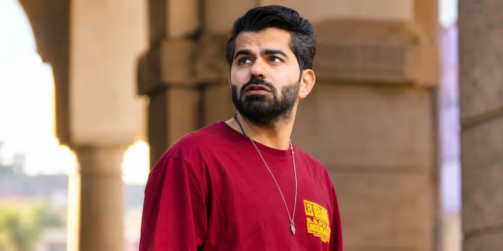 Joe Hattab wearing a red T-shirt and necklace while standing outdoors