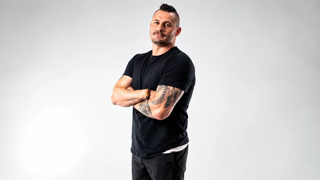 Kane Waselenchuk standing with crossed arms in a black T-shirt and shorts