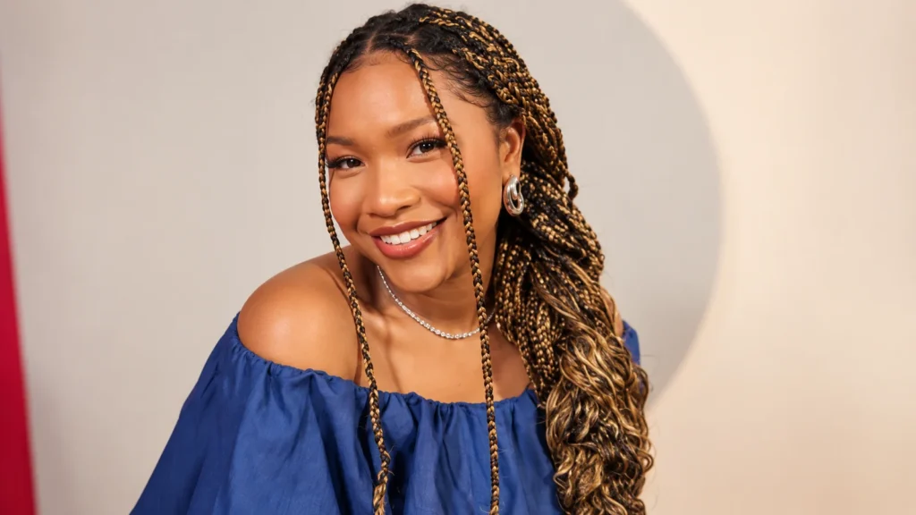 Laya DeLeon Hayes smiling in a blue off-the-shoulder top with braided hair