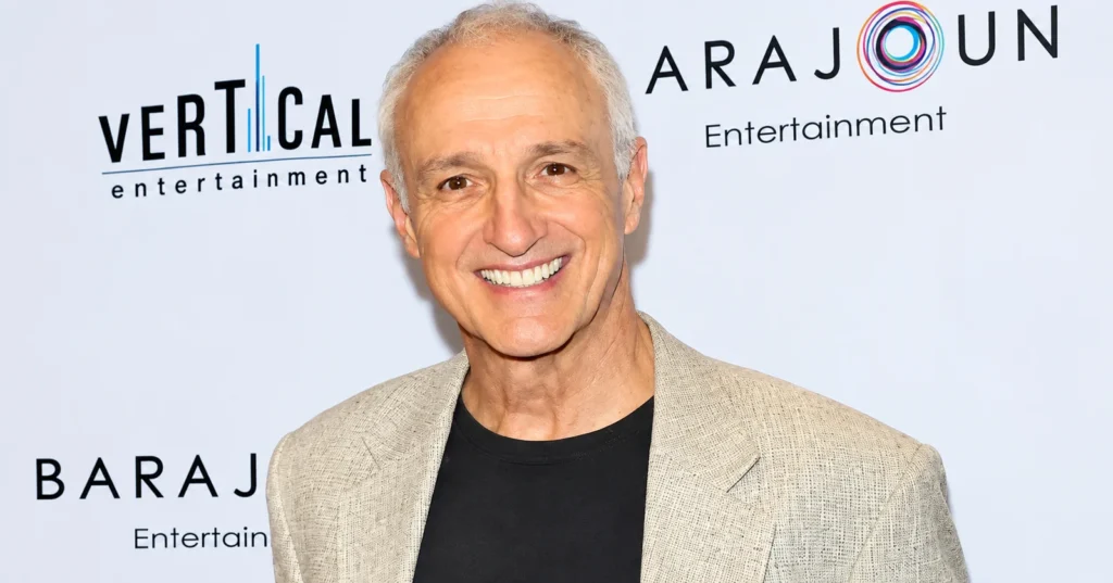 Michael Gross smiling in a beige blazer and black shirt