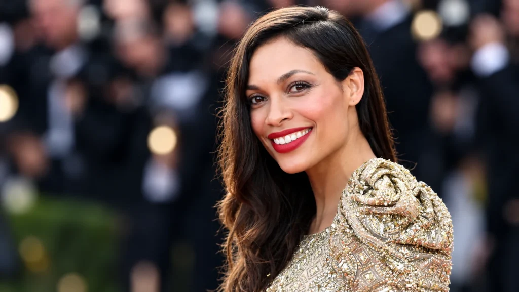 Rosario Dawson smiling on the red carpet in an embellished silver dress