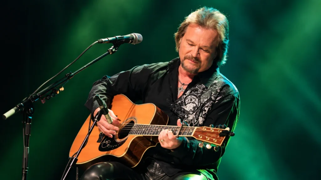 Travis Tritt playing an acoustic guitar during a live concert performance