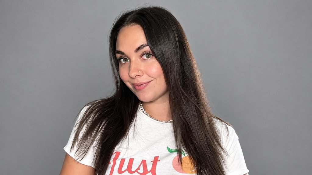 Abby Berner posing in a white graphic T-shirt with long dark hair