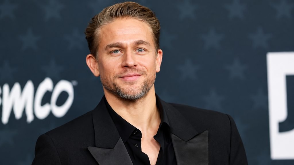 Charlie Hunnam wearing a black suit at a red carpet event