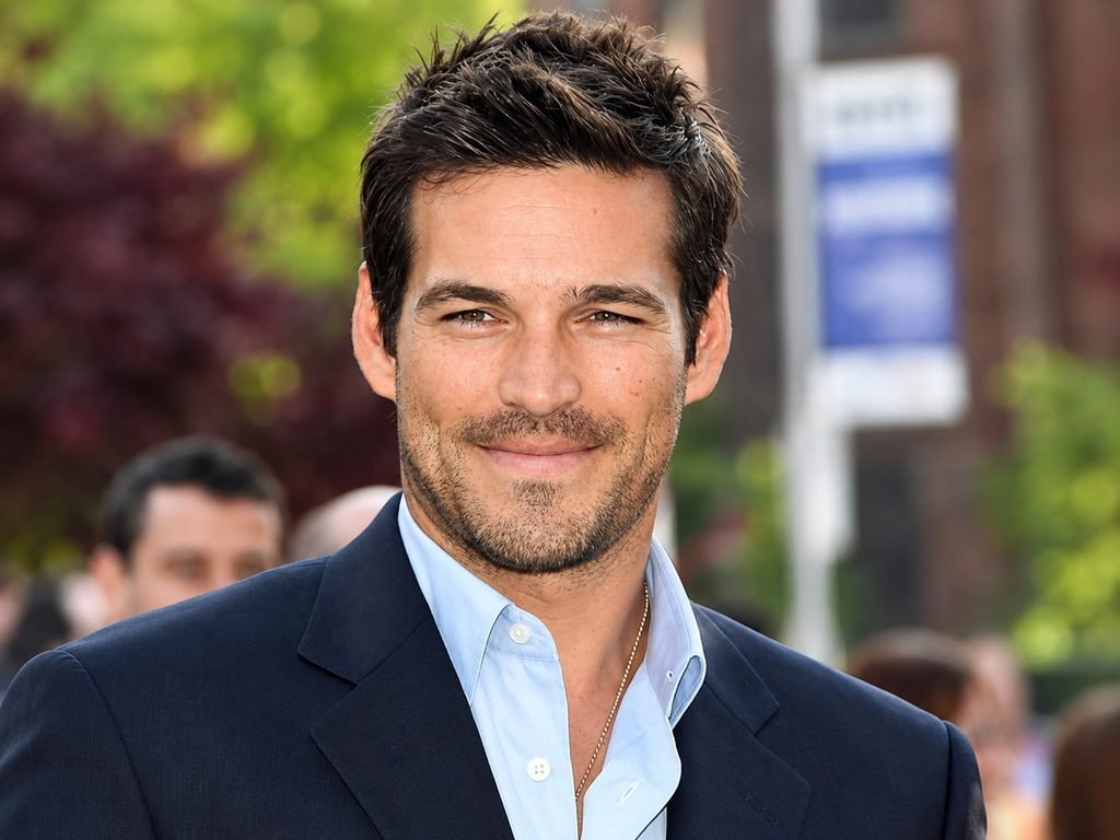 Eddie Cibrian wearing a navy blue suit and light blue shirt at an outdoor event
