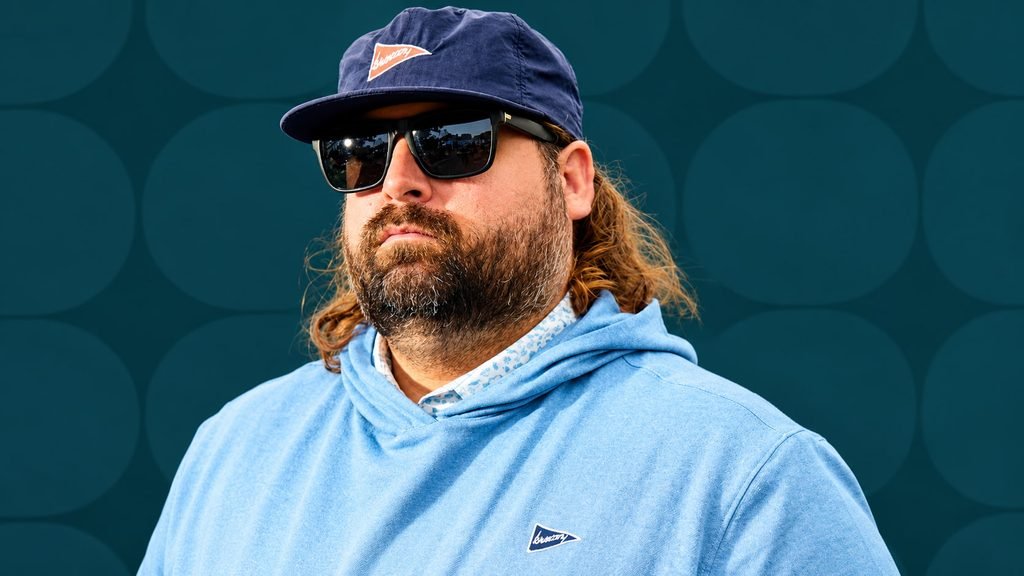 Fat Perez wearing a blue hoodie, navy cap, and sunglasses against a teal background.