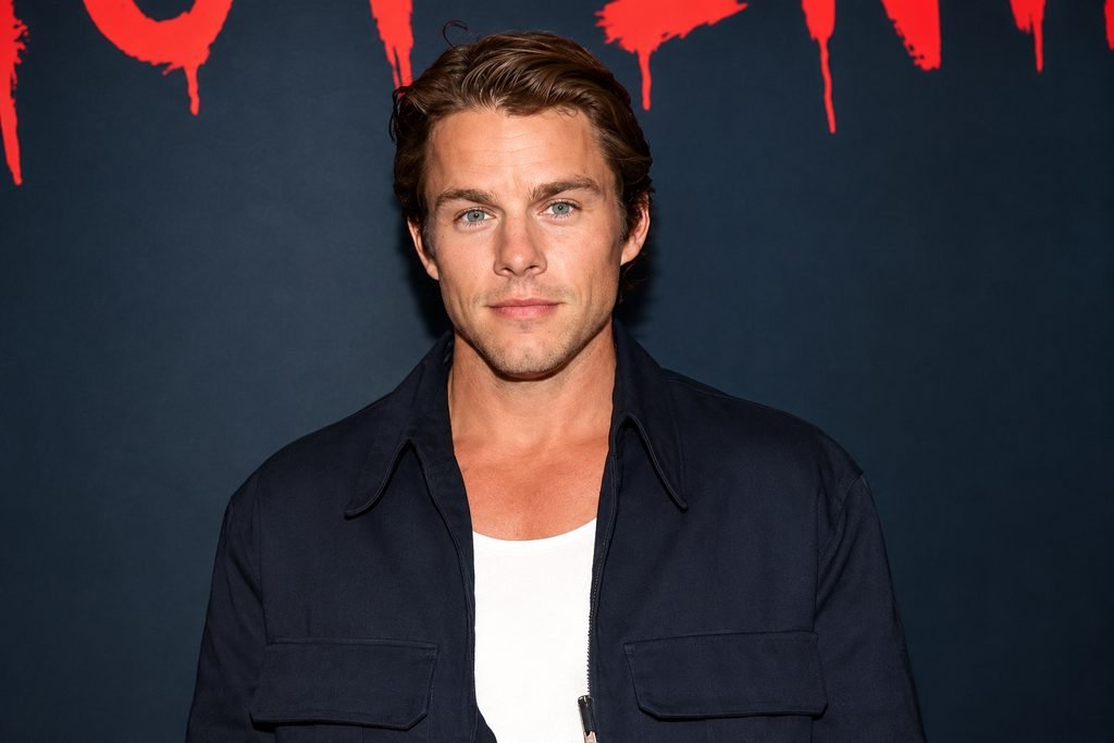 Jake Manley wearing a black jacket over a white shirt at a red-carpet event.