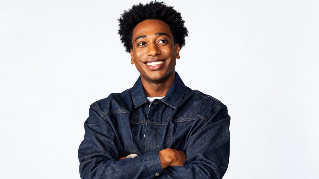 Kevin Langue smiling in a dark denim jacket