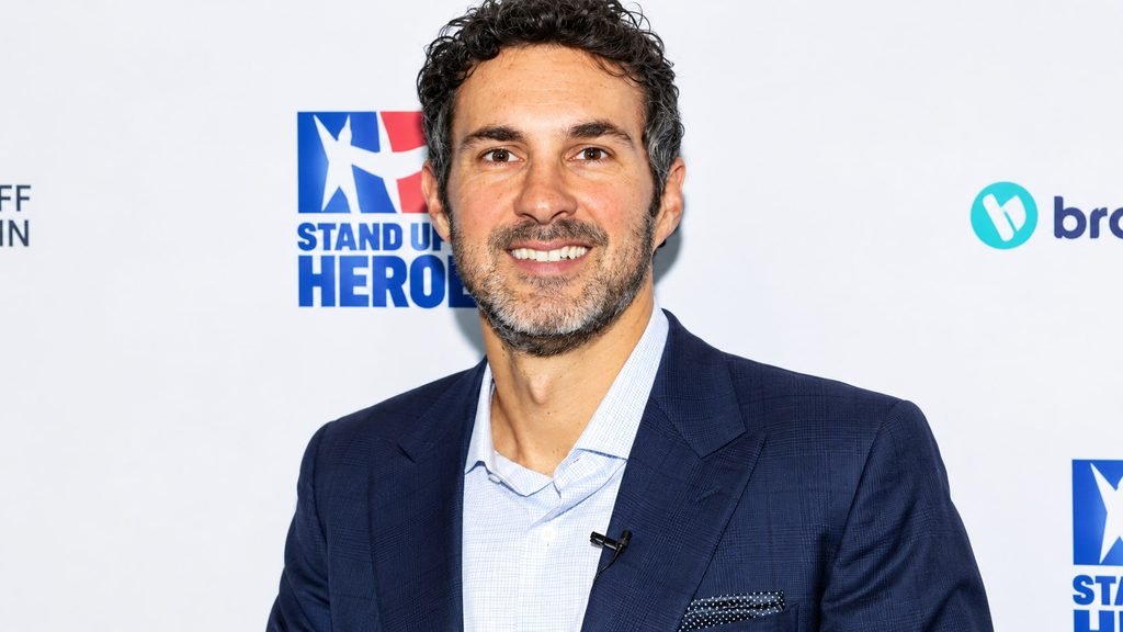 Mark Normand smiling in a navy blue suit at a Stand Up for Heroes event