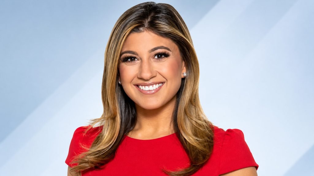 Ruthie Polinsky smiling in a red dress in a professional studio portrait
