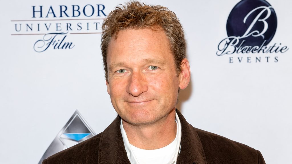 Ryan Stiles smiling in a brown jacket at an event